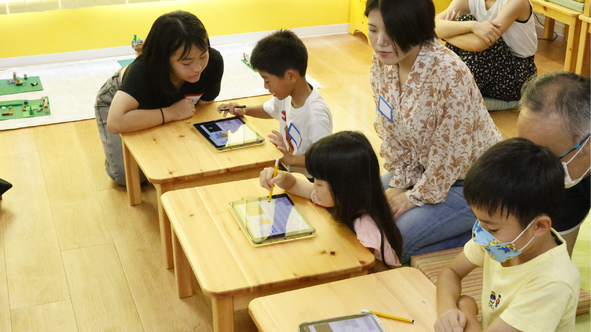 タブレットを使って学ぶ子どもたちと見守る保護者。STEAM教育イベントでの探究の様子