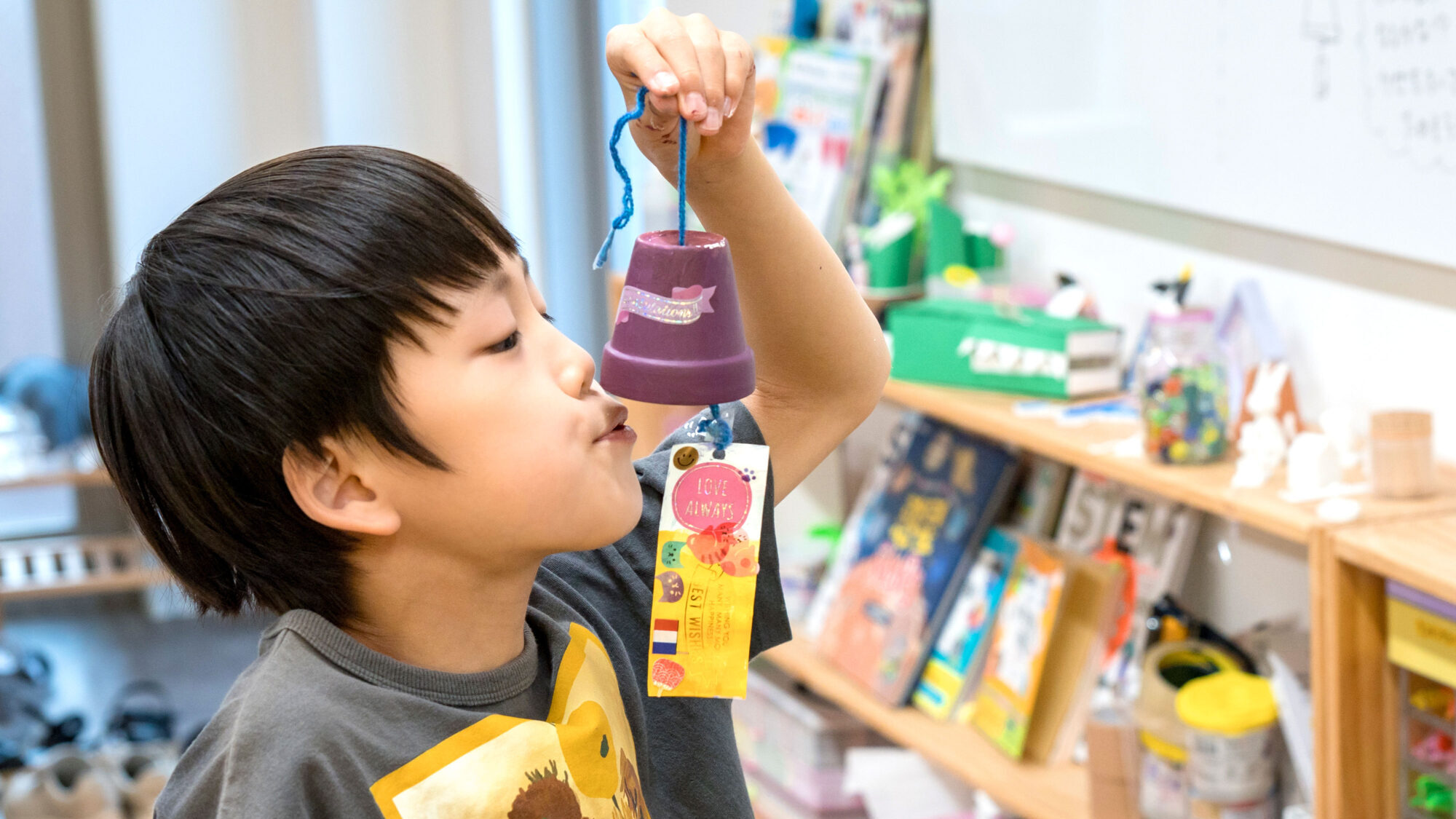 植木鉢風鈴を持ち上げて音を確かめる男の子。親子で楽しめる夏休み工作の様子