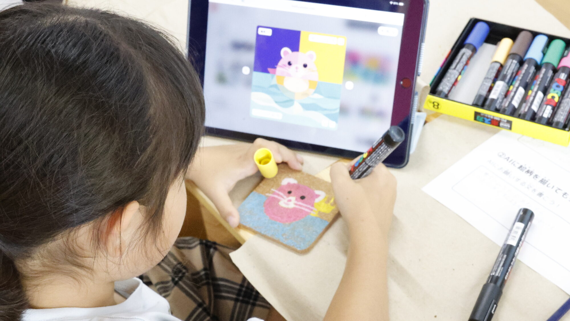 AIで提案されたイラストを見ながら、オリジナルのコースターを自由研究で制作する小学生の様子。