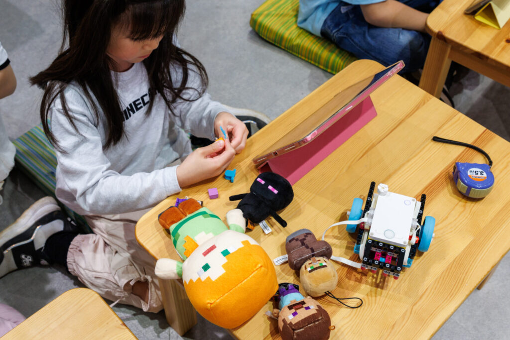 大好きなマインクラフトの人形を横に置き、集中してプログラミングに取り組む女の子