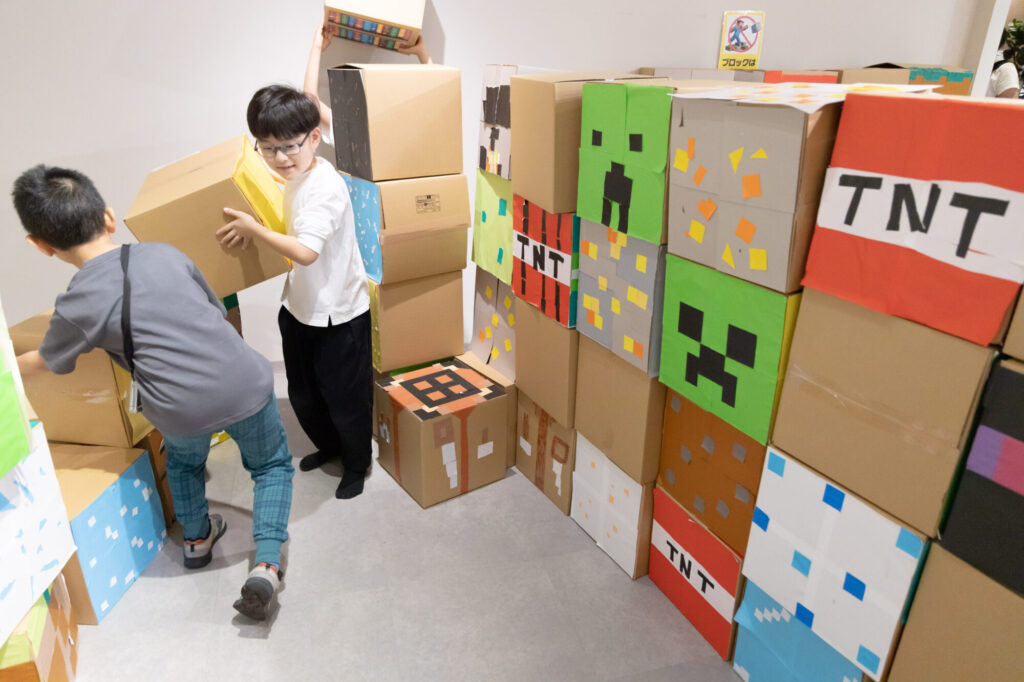 完成した手作りのマイクラ風元素ブロックを積み上げて笑顔で遊ぶ子どもたち