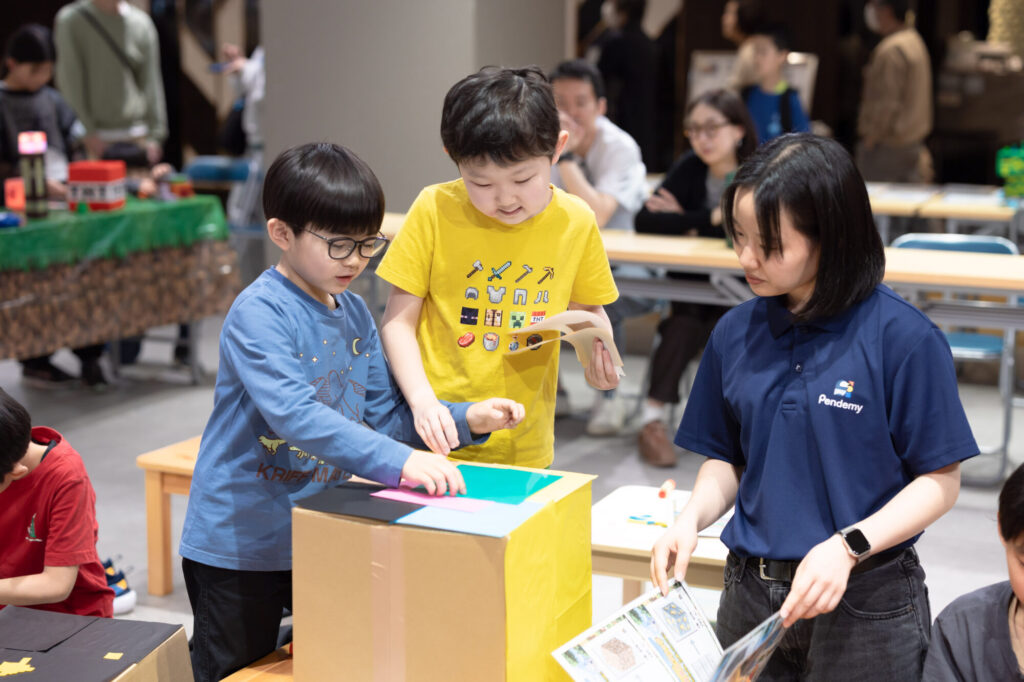 ダンボールと色紙を使ってマイクラ風のオリジナル元素ブロックを工作する小学生